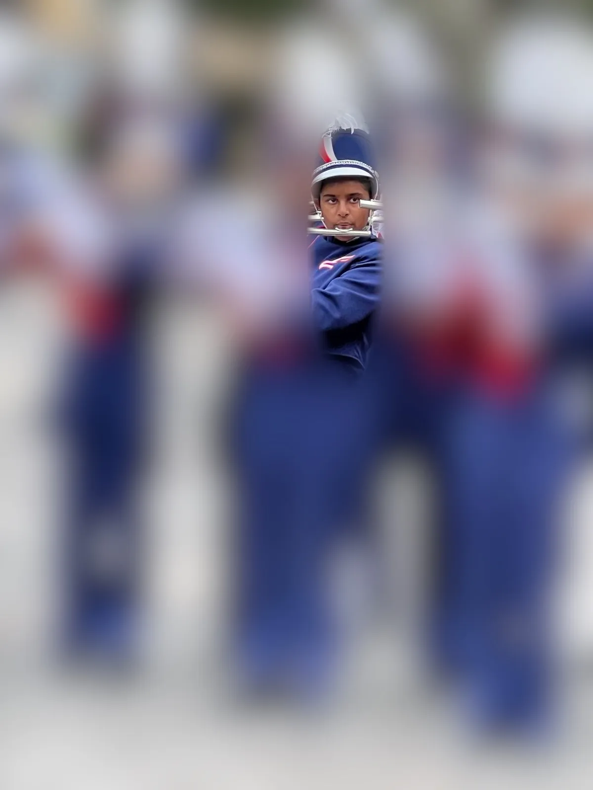 Isha playing flute while marching in a parade, in full uniform.
